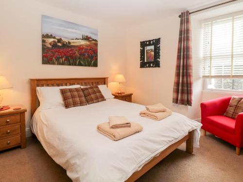 ボウネス・オン・ウィンダミアにあるRaglan Cottageのベッドルーム1室(ベッド1台、赤い椅子付)