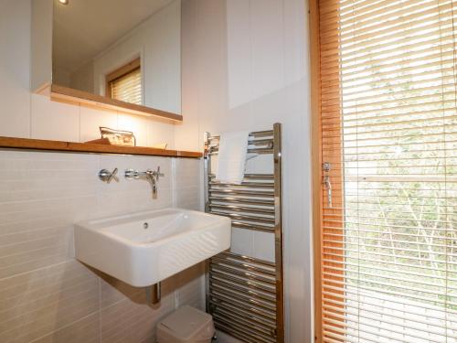 Un baño blanco con lavabo y espejo. en 9 Stonerush Valley, en Looe