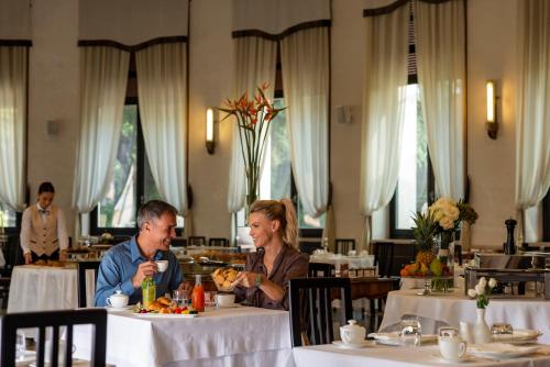 a man and woman sitting at tables in a restaurant at Grand Hotel Castrocaro Longlife Formula in Castrocaro Terme