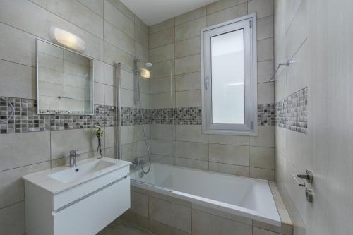 Un baño blanco con bañera y lavabo. en Protaras Villa Alasia, en Protaras