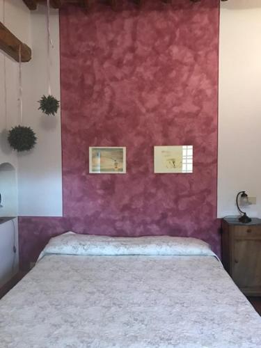 a bed in a room with a red wall at La Locanda del Loggiato in Bagno Vignoni