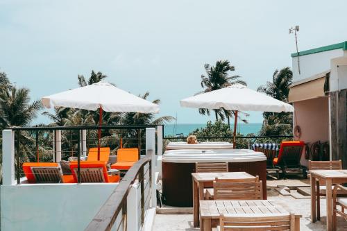 a patio with orange chairs and tables and white umbrellas at Bliss Dhigurah in Dhigurah