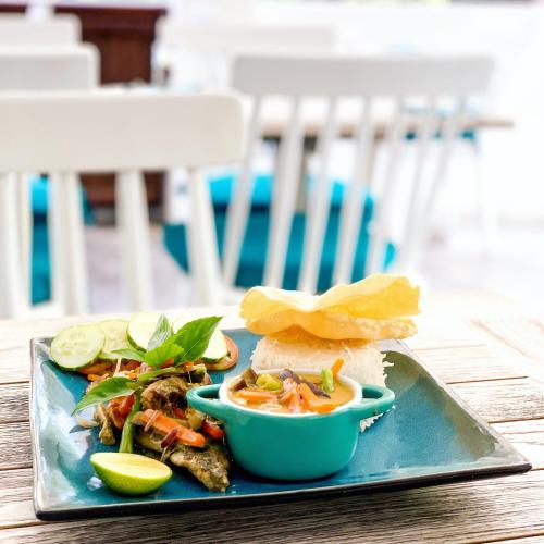 a blue plate with a sandwich and a bowl of food at Bliss Dhigurah in Dhigurah