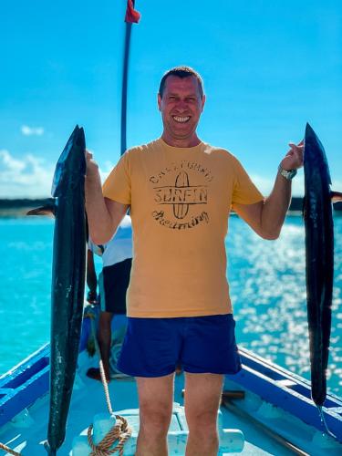 a man standing on a boat holding two dolphins at Bliss Dhigurah in Dhigurah