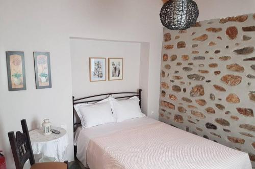 a bedroom with two beds and a rock wall at Nefeli Traditional House in Alonnisos