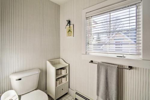 a white bathroom with a toilet and a window at Downtown Charlevoix Duplex half Mi to Lake Michigan in Charlevoix