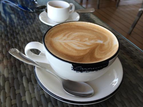 a cup of coffee sitting on a plate with a spoon at Kyriad Paris 12 - Nation in Paris