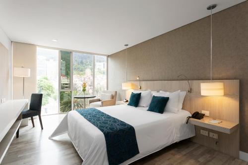 ein Schlafzimmer mit einem großen weißen Bett und einem Schreibtisch in der Unterkunft Hotel bh Bicentenario in Bogotá