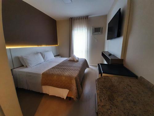 a hotel room with a bed and a television at Caravaggio Praia Hotel in Florianópolis
