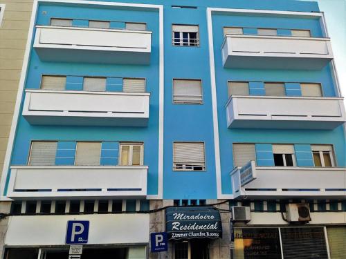 a blue building with white windows and a parking sign at Residencial Miradoiro Guest House in Portimão