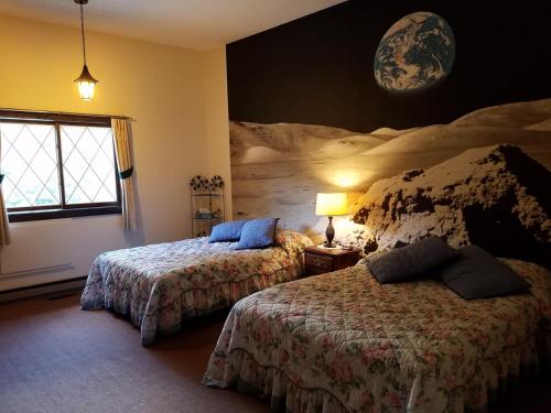 un dormitorio con 2 camas y un planeta en la pared en Kancamagus Swift River Inn, en Albany
