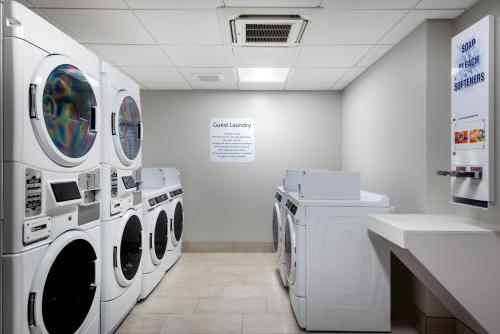 a laundry room with three washing machines and a sink at Holiday Inn Express & Suites Santa Ana - Orange County by IHG in Santa Ana