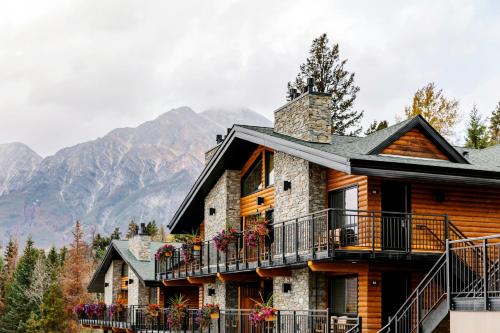a log house with a balcony and mountains in the background at Pyramid Lake Lodge in Jasper