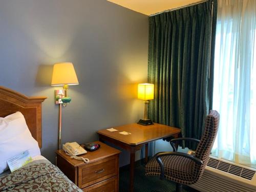 ein Hotelzimmer mit einem Bett und einem Schreibtisch mit einer Lampe in der Unterkunft Days Inn by Wyndham Jonesboro AR in Jonesboro
