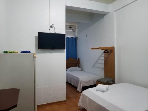 a room with two beds and a tv in it at Hotel Chalé Ji-Parana in Ji-Paraná