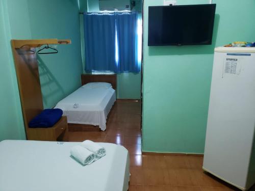 um pequeno quarto com 2 camas e uma televisão em Hotel Chalé Ji-Parana em Ji-Paraná