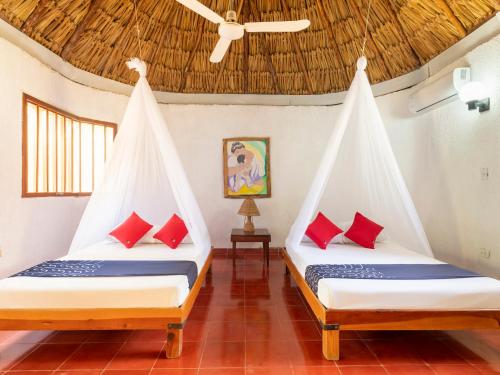 two beds in a room with red pillows at Hotel Villas del Ángel in San José