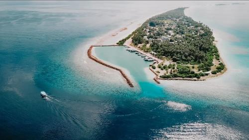 an island in the ocean with a boat in the water at Bliss Dhigurah in Dhigurah