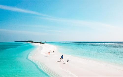 a group of people walking on a white beach at Bliss Dhigurah in Dhigurah