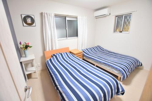 大阪市にあるAozora HOTEL in tsuruhashiの青と白のストライプを用いた小さな部屋のベッド2台
