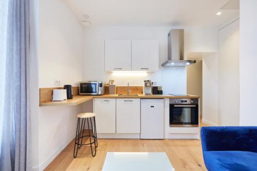a kitchen with white cabinets and a blue couch at Résidence Colonel in Laval