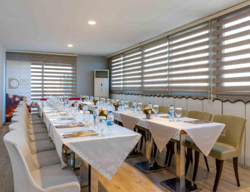 a long dining room with white tables and chairs at Dies Hotel in Diyarbakır