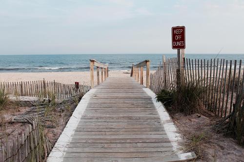 a wooden boardwalk leading to the beach with a for sale sign at Holiday Inn Express Stony Brook-Long Island by IHG in Centereach