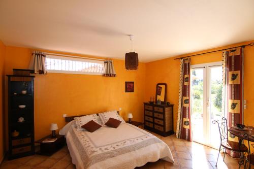 Mas Uranie في Le Soler: غرفة نوم بجدران صفراء وسرير ونافذة