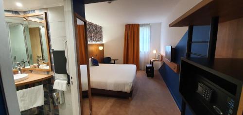 a hotel room with a bed and a bathroom at Kyriad Aix Les Milles - Plan de Campagne in Bouc-Bel-Air