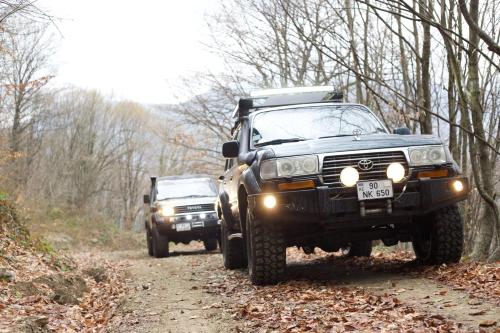 two trucks on a dirt road in the woods at Marxal Resort & Spa in Sheki