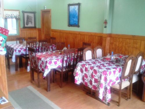 uma sala de jantar com mesas e cadeiras com toalha de mesa vermelha e branca em Hostal El Rincón em Puerto Natales