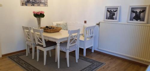 a dining room table with chairs and a vase of flowers on it at Ferienbauernhof De Slaaphoeve in Emlichheim