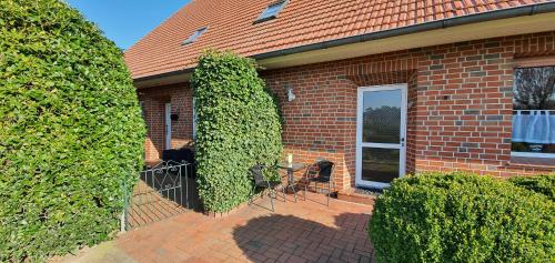 a brick house with two bushes next to a door at Ferienbauernhof De Slaaphoeve in Emlichheim