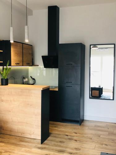 a kitchen with black cabinets and a wooden counter at Property Apart - Soft Lofty Legnicka Centrum in Wrocław