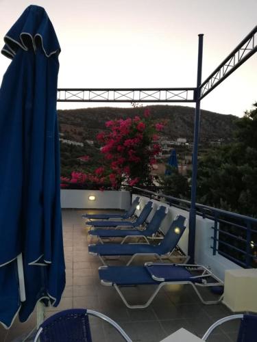 a row of blue chairs and umbrellas on a balcony at Heliotopos Apartments in Tolo