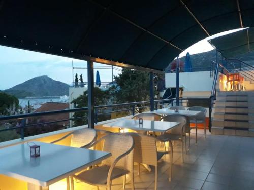 a restaurant with tables and chairs on a balcony at Heliotopos Apartments in Tolo