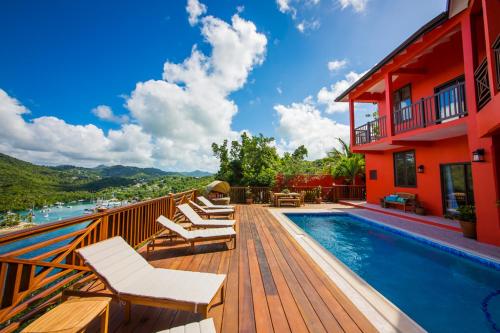a deck with chairs and a swimming pool next to a building at Villa On The Bay - Relaxed Elegance in Marigot Bay