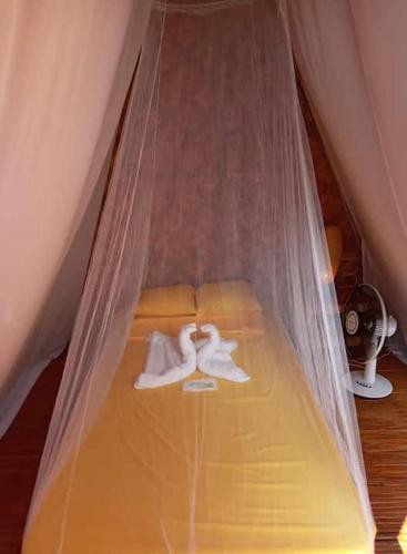 a bed with a net with towels on it at SHUKRAN Apartelle in Siquijor