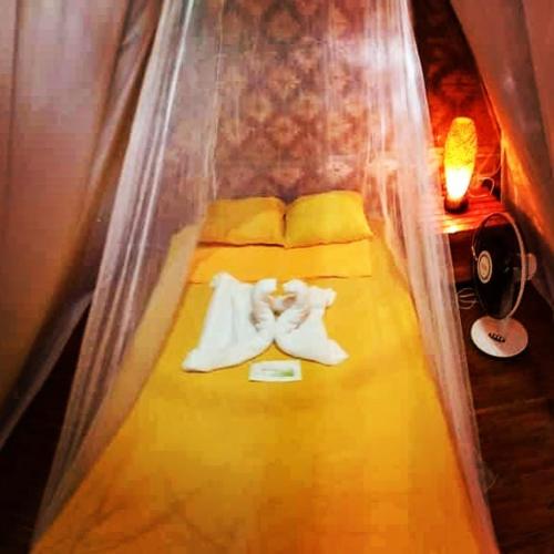 a bed in a room with yellow sheets and pillows at SHUKRAN Apartelle in Siquijor