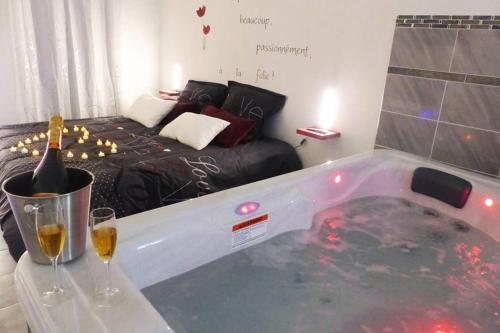 a bath tub with a bottle of wine and two glasses at Nuit romantique avec Jacuzzi SPA privatif proche TOULOUSE in Auterive
