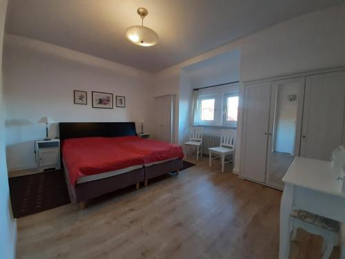 バート・ザクサにあるFerienwohnung Stricker Typ Eのベッドルーム1室(赤いベッド1台、テーブル、椅子付)