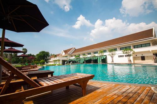 a large swimming pool with benches and an umbrella at Bangsaen Heritage Hotel - SHA Plus Certified in Bangsaen