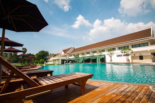 una gran piscina con bancos y sombrilla en Bangsaen Heritage Hotel - SHA Plus Certified en Bangsaen