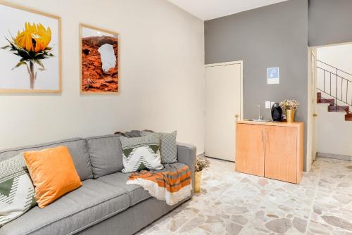 a living room with a gray couch and orange pillows at Casa Alexia in Guadalajara