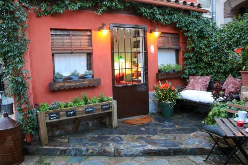a red house with a door and a couch outside at Suite Garden House in Santa Cristina d'Aro