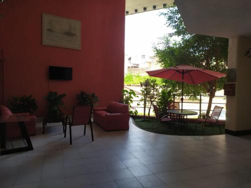 a lobby with a table and chairs and an umbrella at Hotel Cabildos in Tapachula