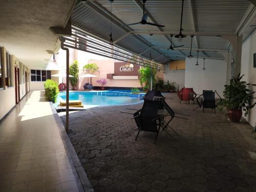 une chambre avec une piscine et des chaises dans un bâtiment dans l'établissement Hotel Cabildos, à Tapachula