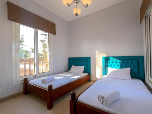 two twin beds in a room with two windows at Exotic Retreat 2 BR Apartment in Water Side Lagoon Pool in Hurghada