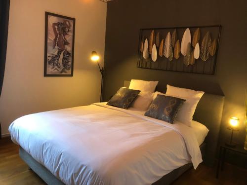 a bedroom with a large white bed with two pillows at Au Coeur du Marché 4 étoiles in Fécamp