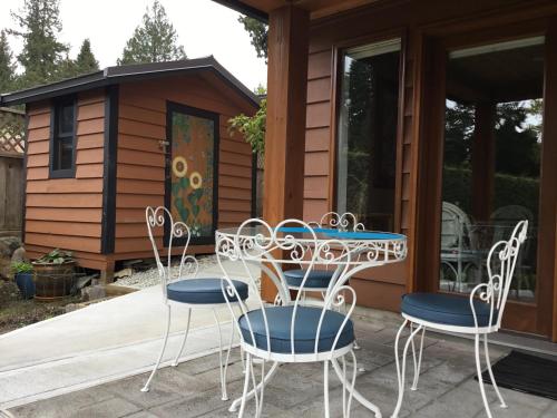 a patio with a table and chairs in front of a cabin at Nestledown B&B in Halfmoon Bay